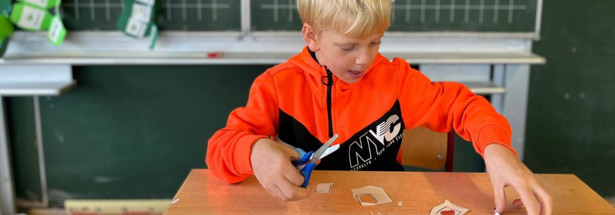 Ein Junge mit einer Schere beim Basteln. In der Heilpädagogischen Tagesstätte werden die Kinder nach Schulschluss gefördert.