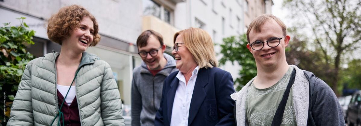 Gruppe von Menschen mit und ohne Behinderung geht fröhlich die Straße entlang. Ehrenamt bei der Lebenshilfe Würzburg e.V. fördert Selbstbestimmung und Inklusion.